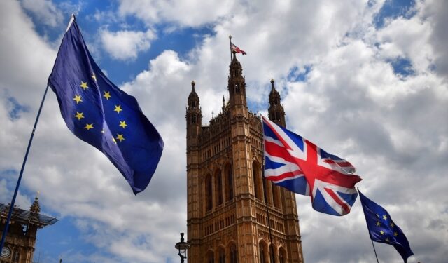 The European Union and UK flags flying outside tje House of Parliament in London as part of a Brexit protest